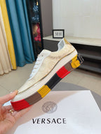 Side view of white and gold low-top sneakers with white laces and multicolor striped platform sole
