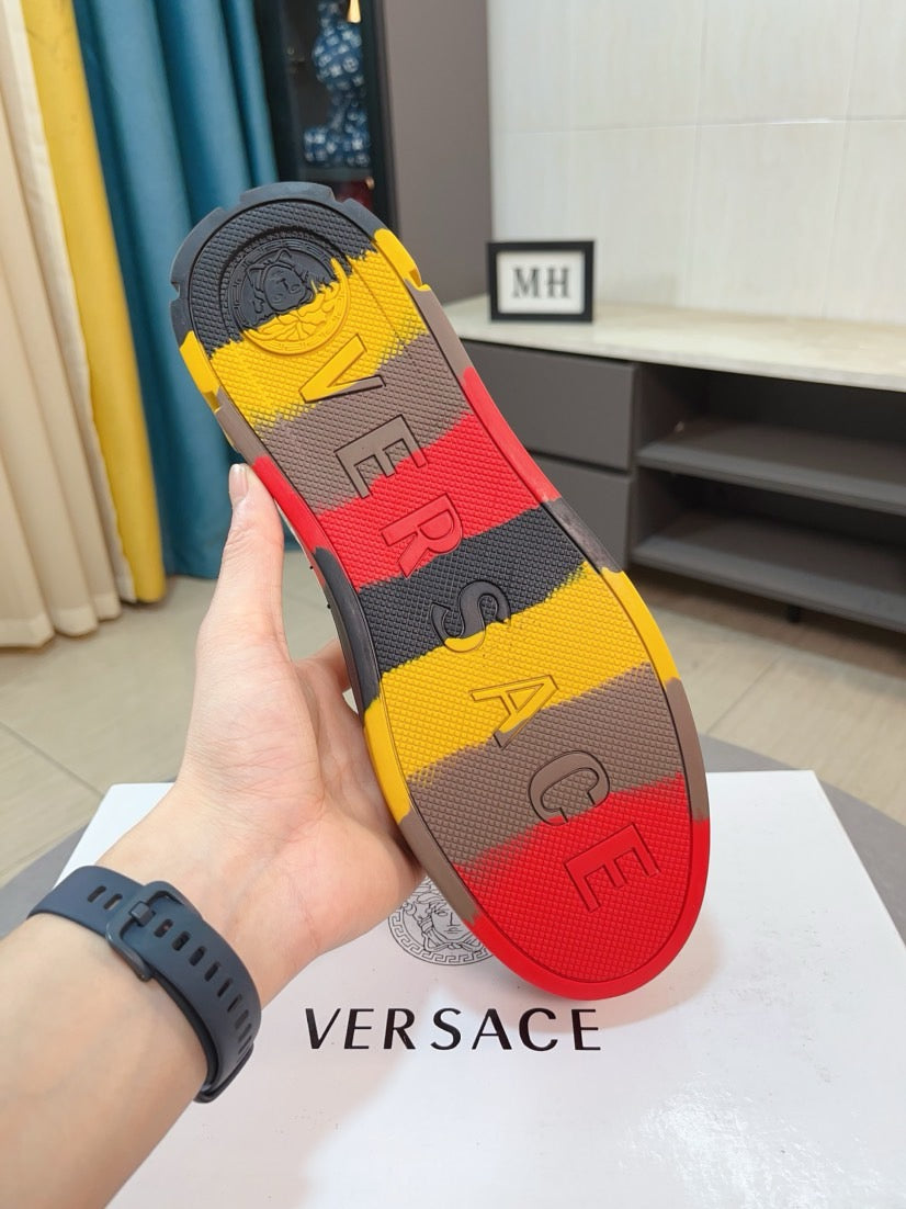 Sole view of white and gold sneaker with colorful rubber tread and dark logo pattern