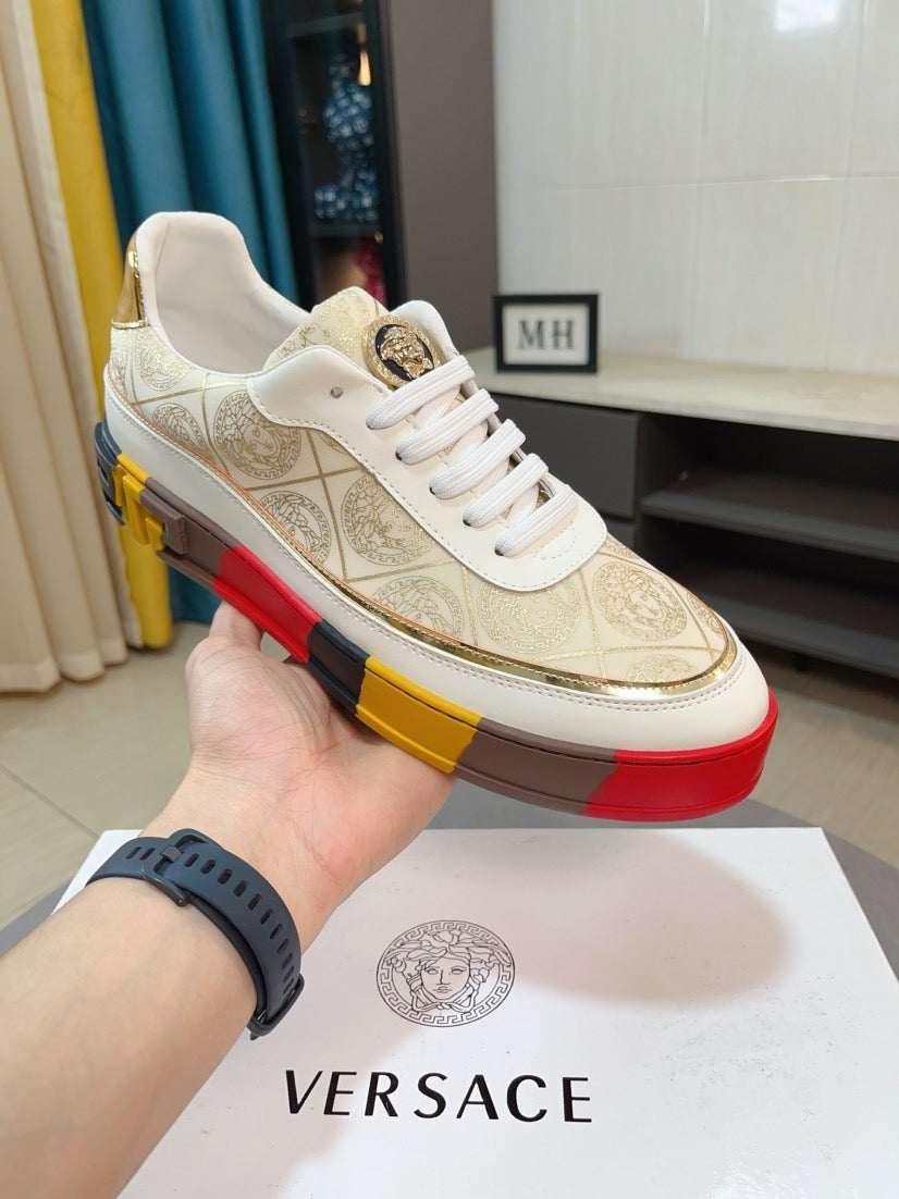 Gold and white low-top sneakers with white laces, ornate upper, gold logo badge on side