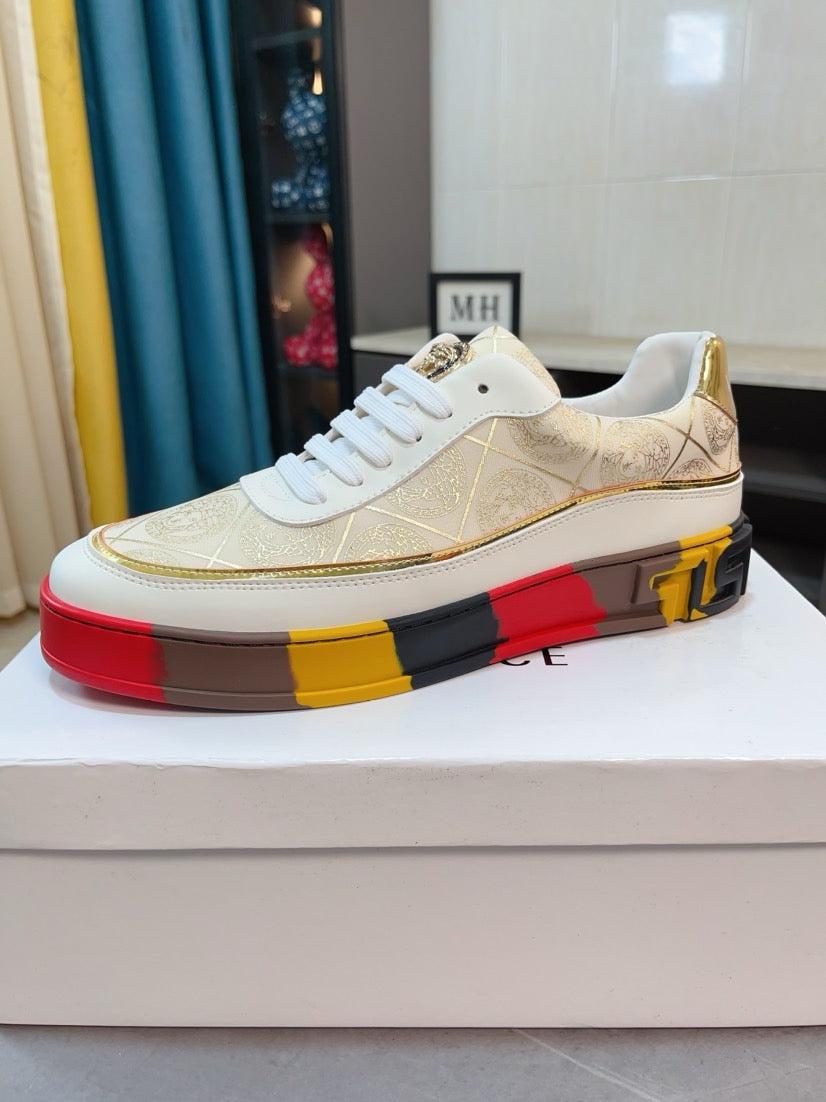 White and gold low-top sneakers with gold-pattern upper and white laces, red yellow black sole