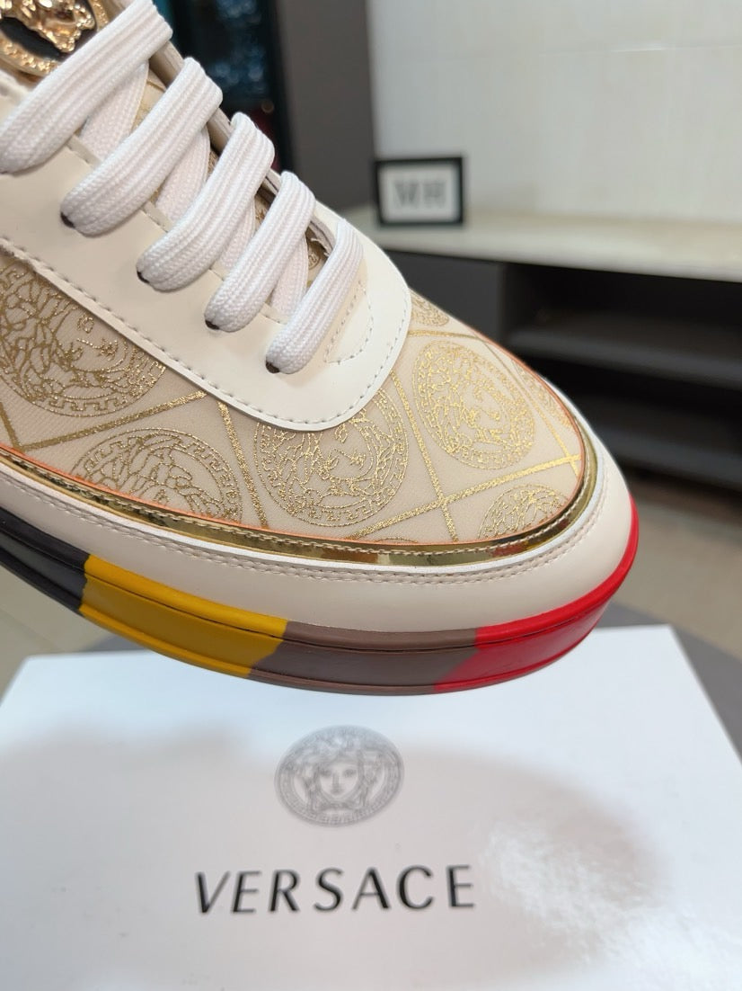 Close-up of white leather low-top sneaker upper with gold ornate print and white laces