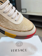 Close-up of white leather low-top sneaker upper with gold ornate print and white laces