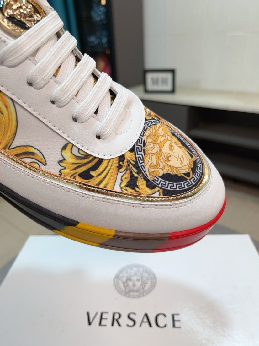 White luxury sneakers close-up with gold baroque print and cushioned platform sole.