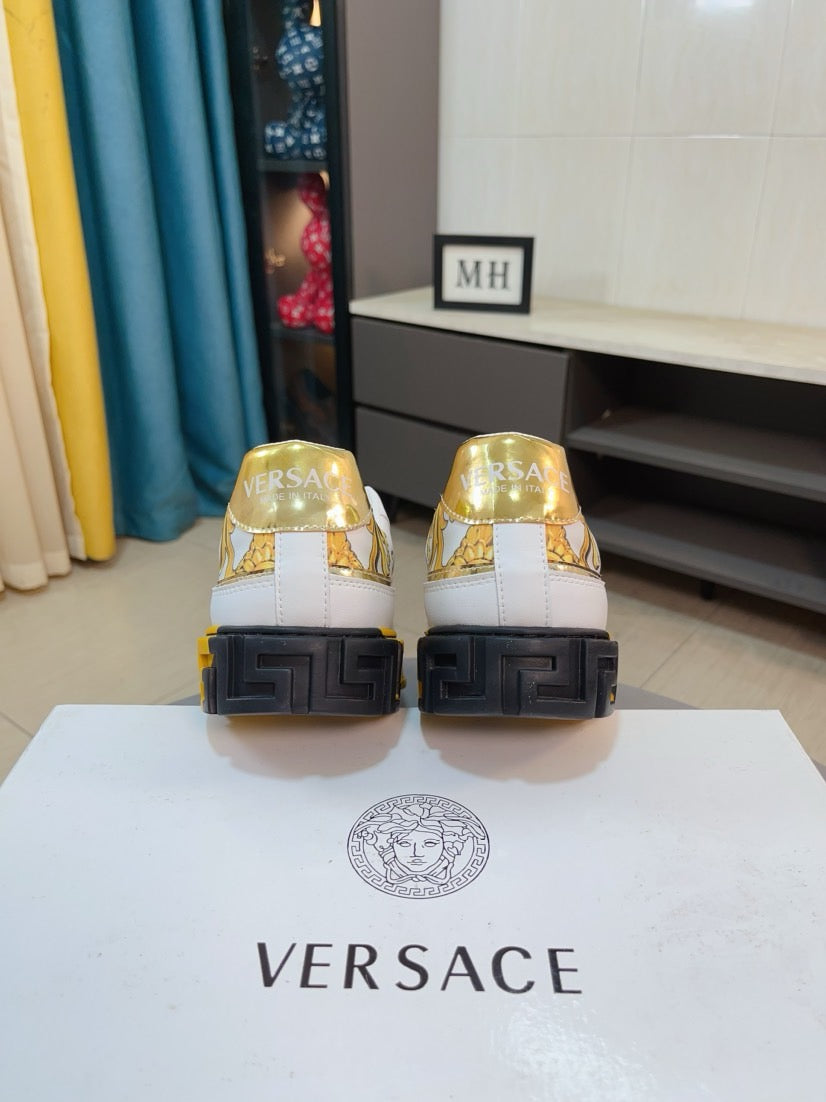 Pair of luxury sneakers with gold logo on heels and black textured outsole.
