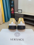 Pair of luxury sneakers with gold logo on heels and black textured outsole.