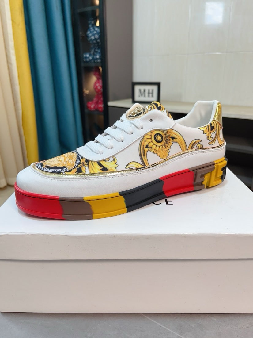 White luxury sneakers with gold baroque upper, medallion detail, and red/yellow platform sole.