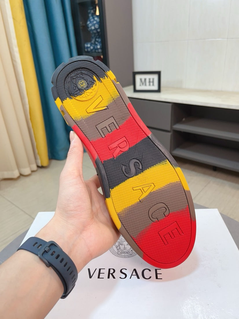 Luxury sneaker outsole view with yellow, red, and black rubber tread and lettering.
