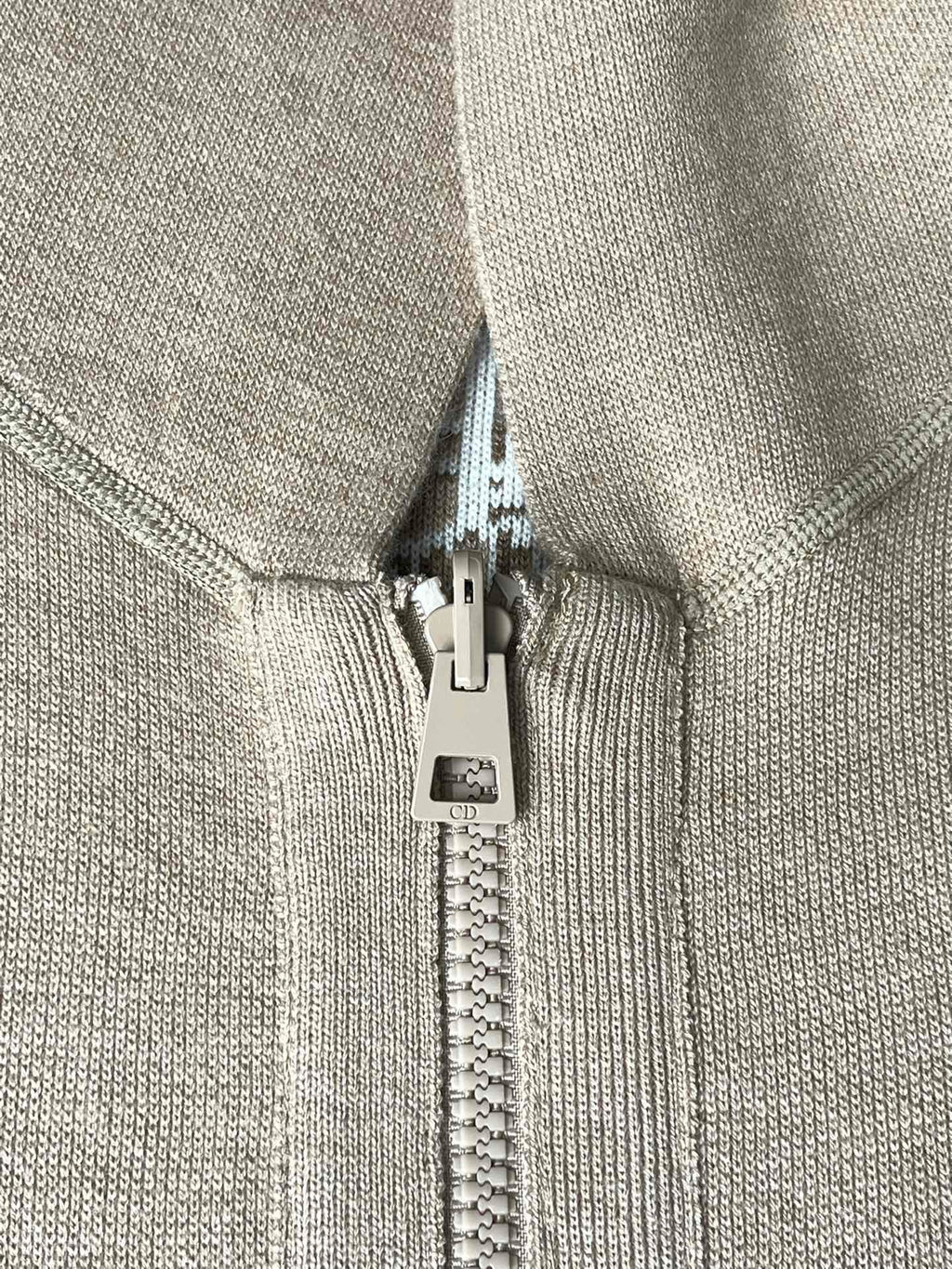 Beige zip pull and zipper on hooded jacket with fabric-lined hood