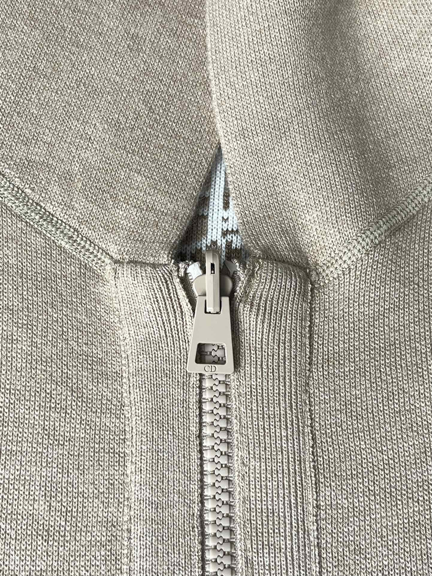 Beige zip pull and zipper on hooded jacket with fabric-lined hood