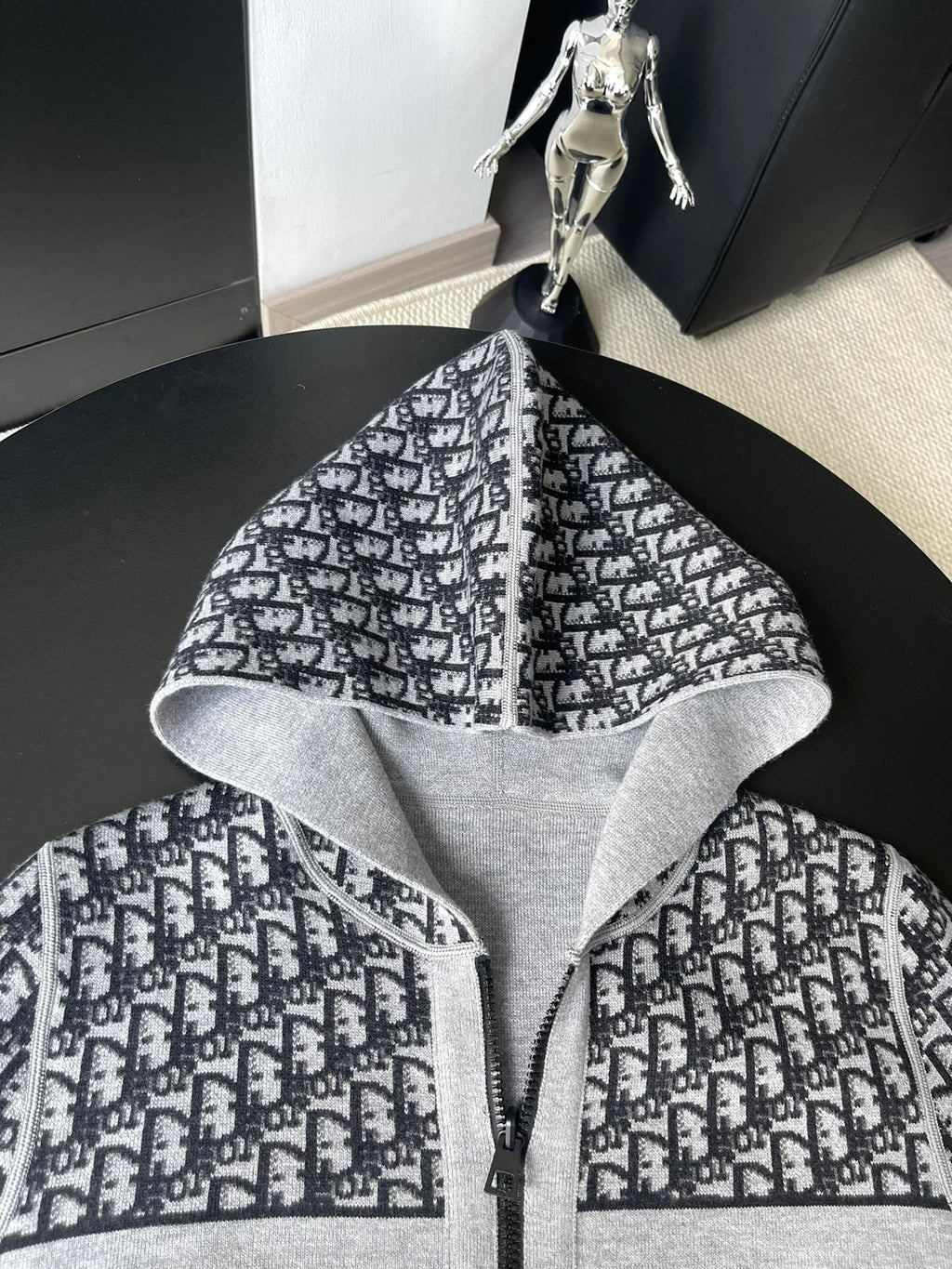 Black and white patterned hooded zip-up sweater with open hood and central zipper