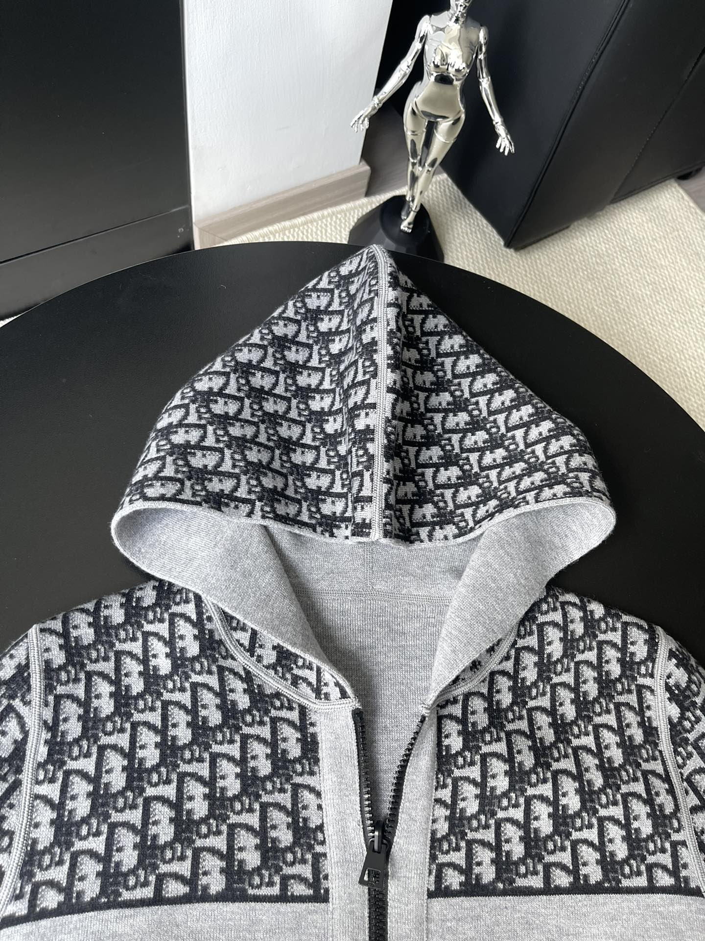 Black and white patterned hooded zip-up sweater with open hood and central zipper