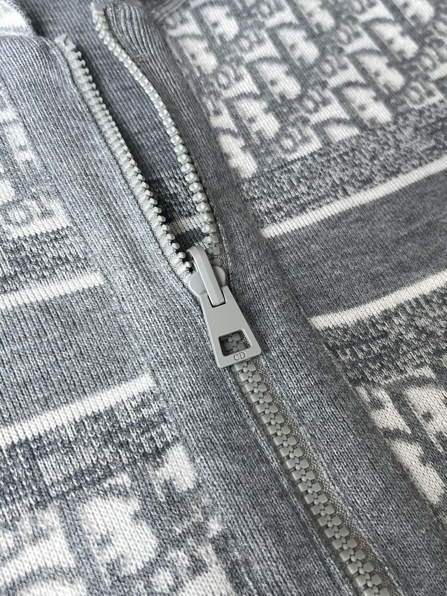 Gray hoodie zipper detail with metal pull on patterned fabric