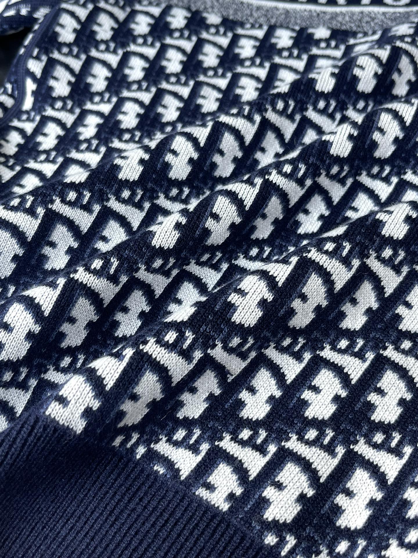 Close-up of navy Dior jacquard knit with white motif repeat