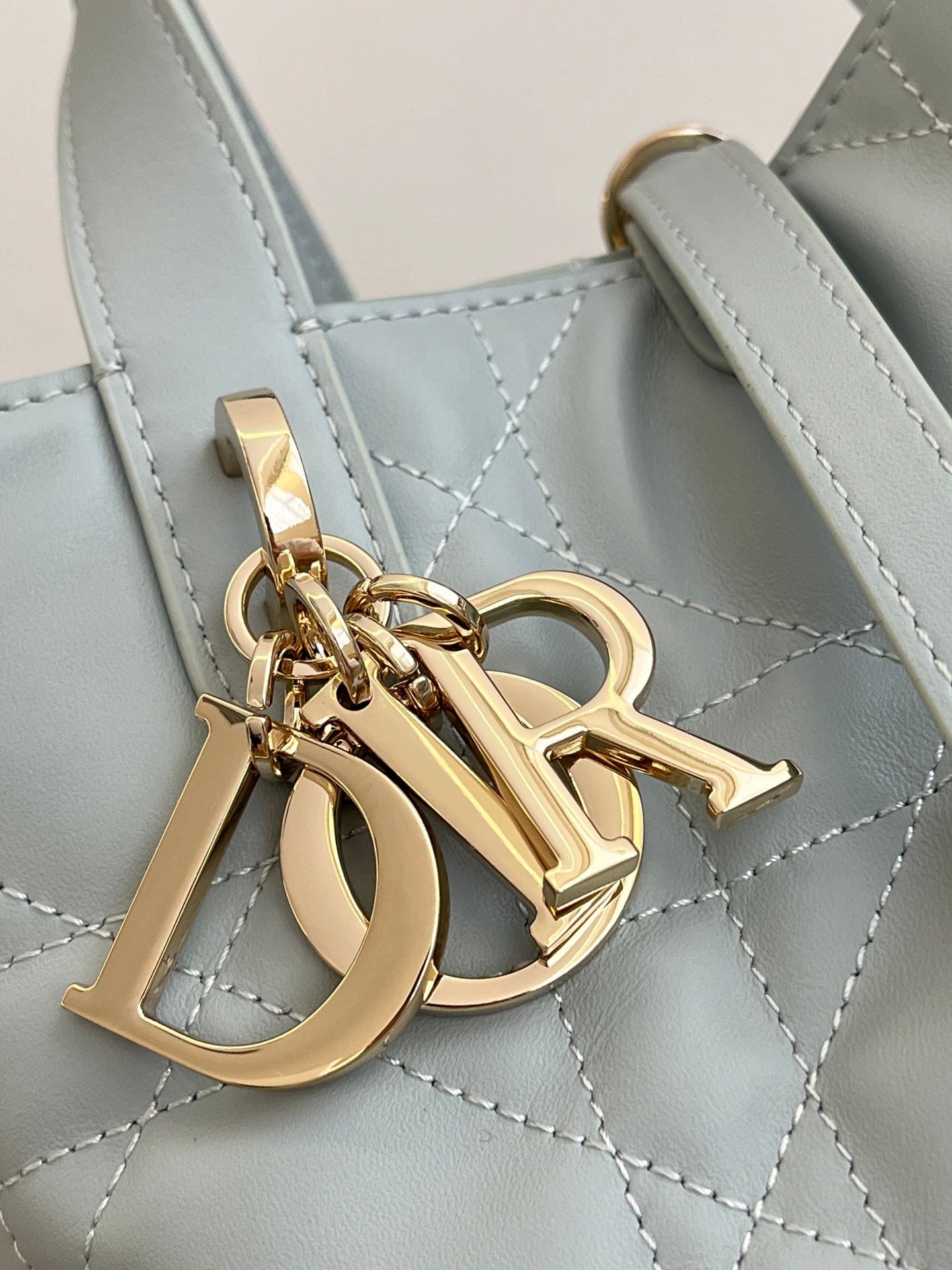 Dior light-blue handbag detail with gold-tone logo hardware and stitched quilt pattern