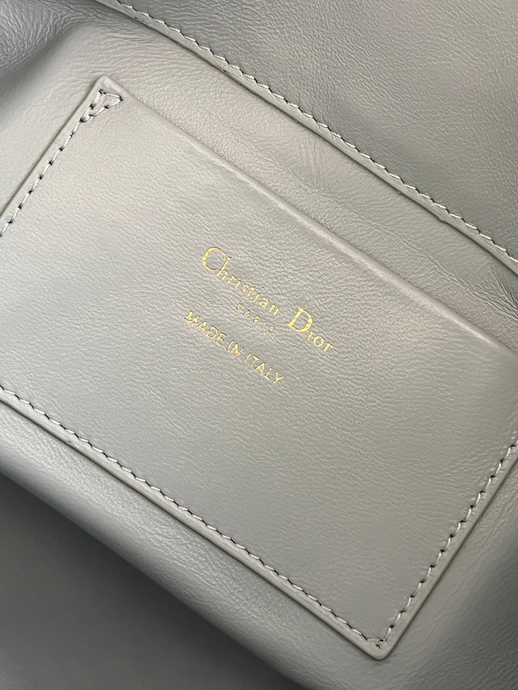 Dior light-blue leather interior label with gold 'Christian Dior' text and stitching