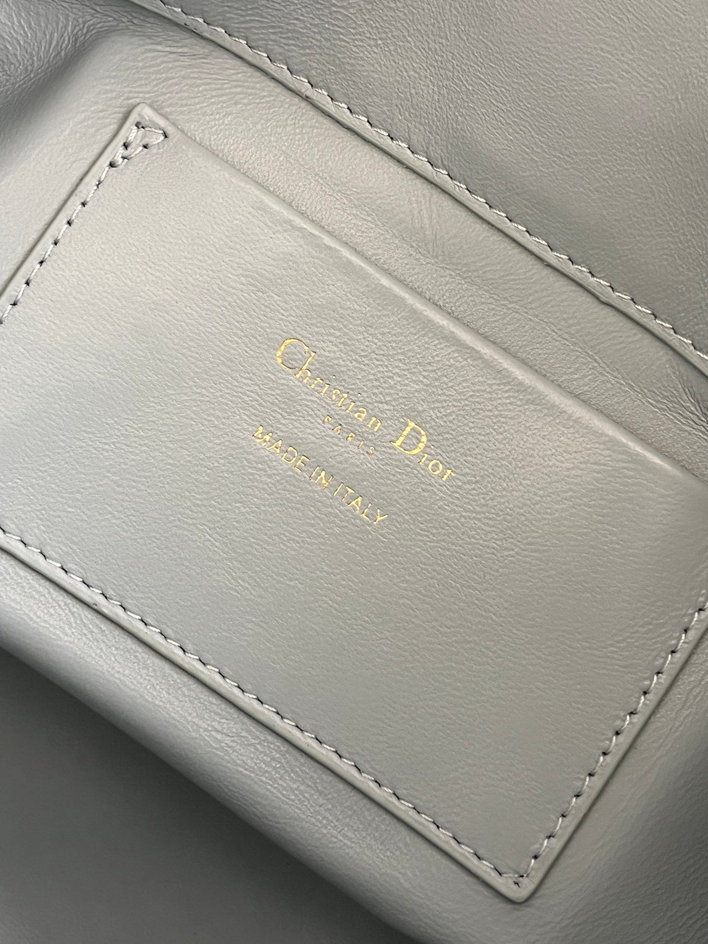 Dior light-blue leather interior label with gold 'Christian Dior' text and stitching