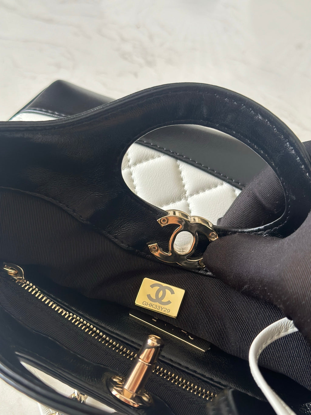 Chanel bag close-up showing gold-toned zipper hardware and black quilted interior