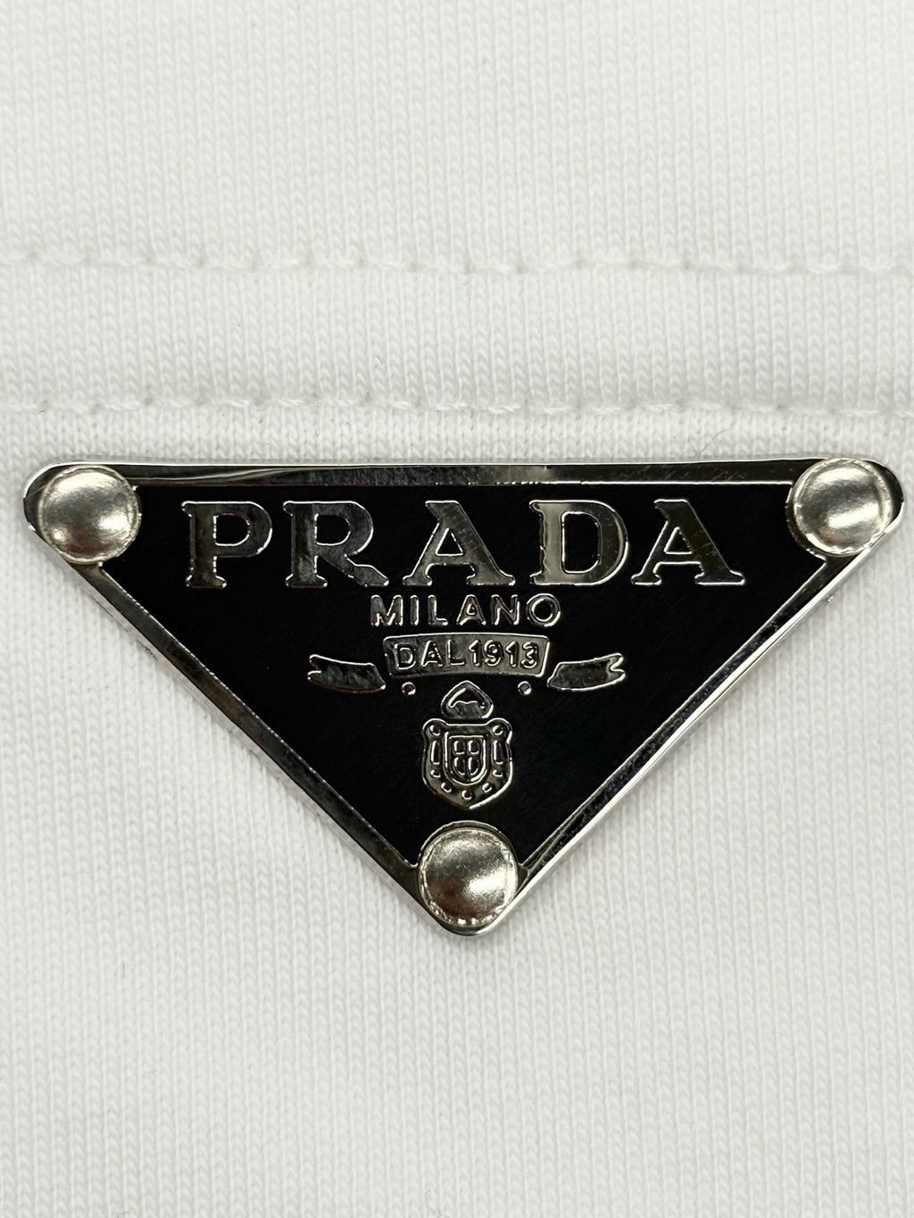 Prada metal triangle logo badge with PRADA MILANO detail on white T-shirt