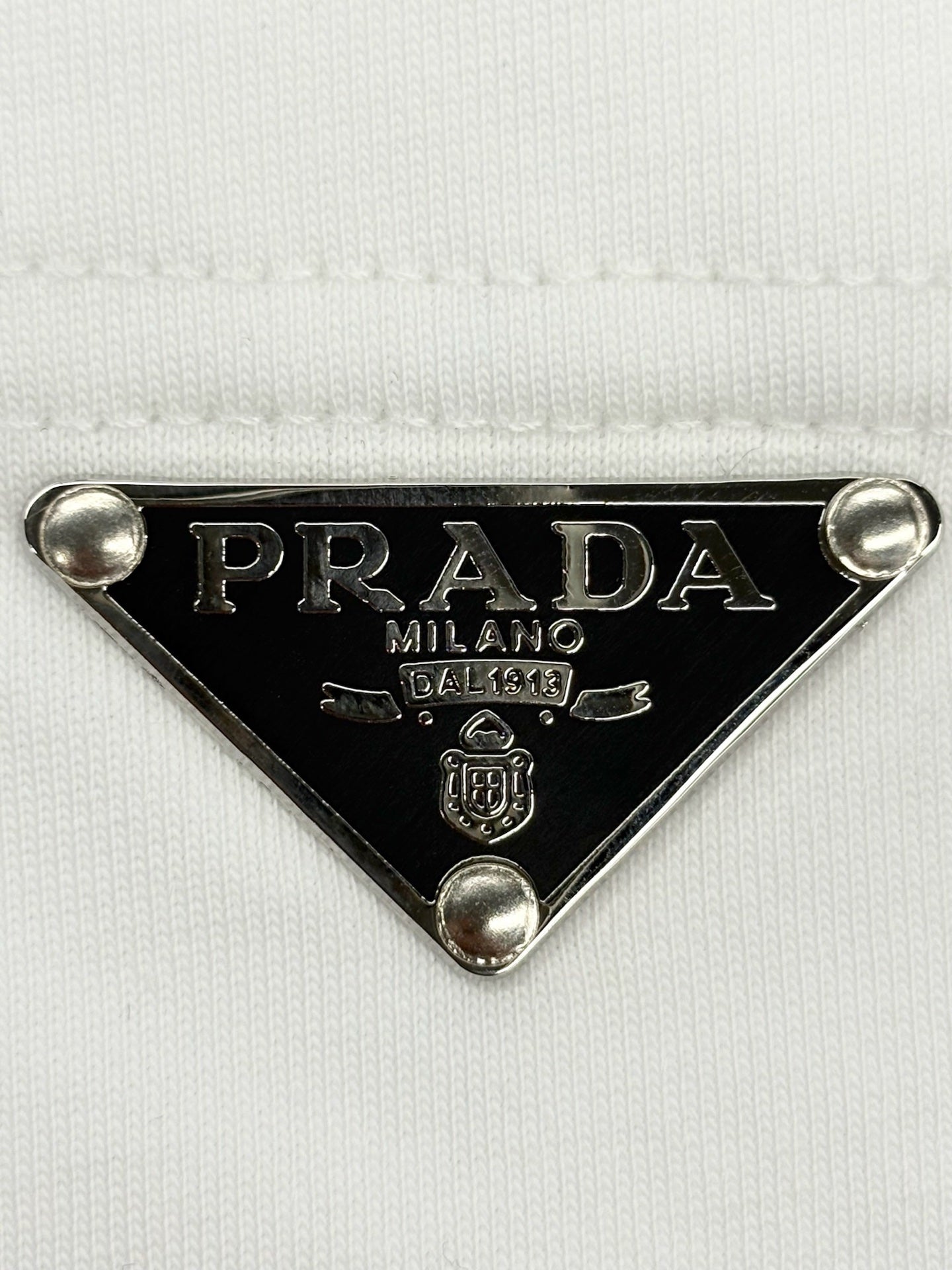 Prada metal triangle logo badge with PRADA MILANO detail on white T-shirt