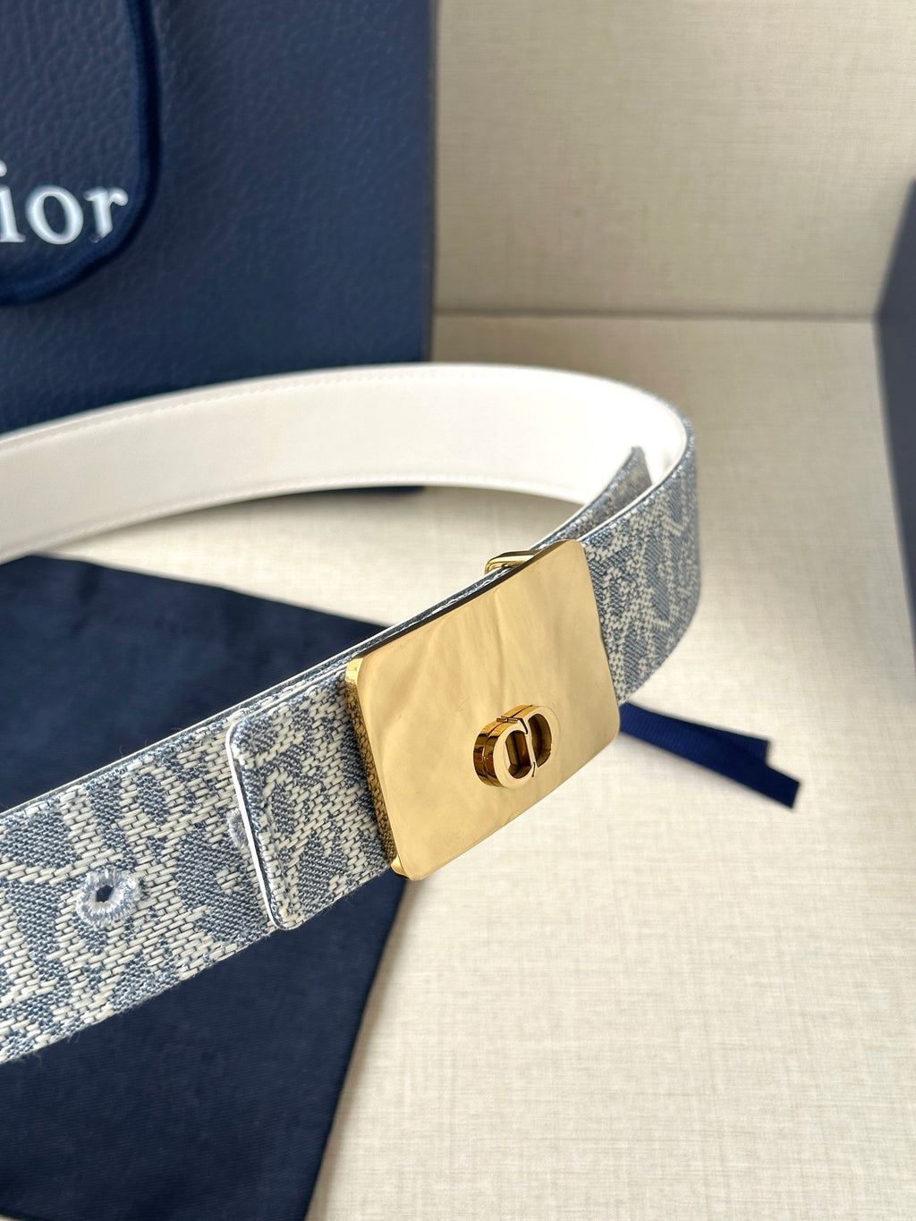 Dior belt close-up: blue monogram strap with gold-tone buckle