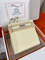 Cream leather handbag with front flap, rectangular silver clasp, top handle
