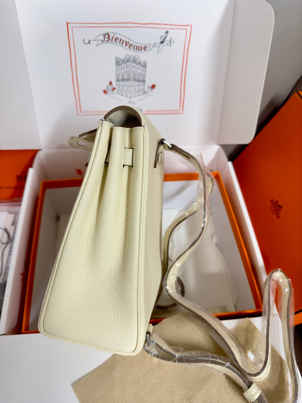 Cream leather handbag with top handle and shoulder strap, side profile