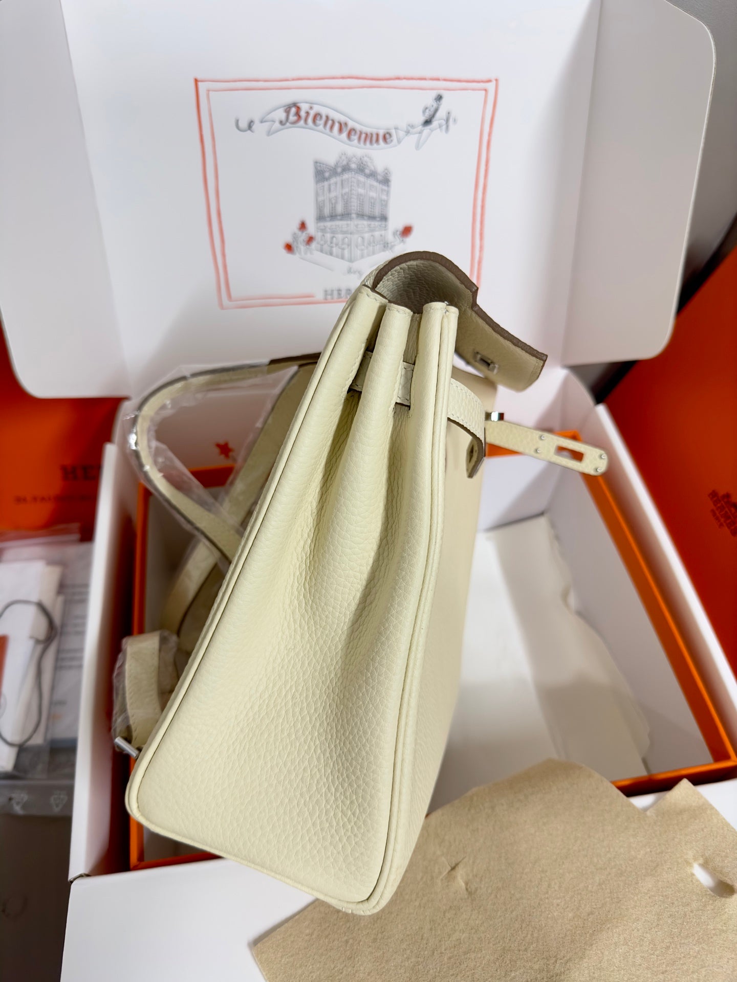 Cream leather handbag with top handles and adjustable shoulder strap, back view