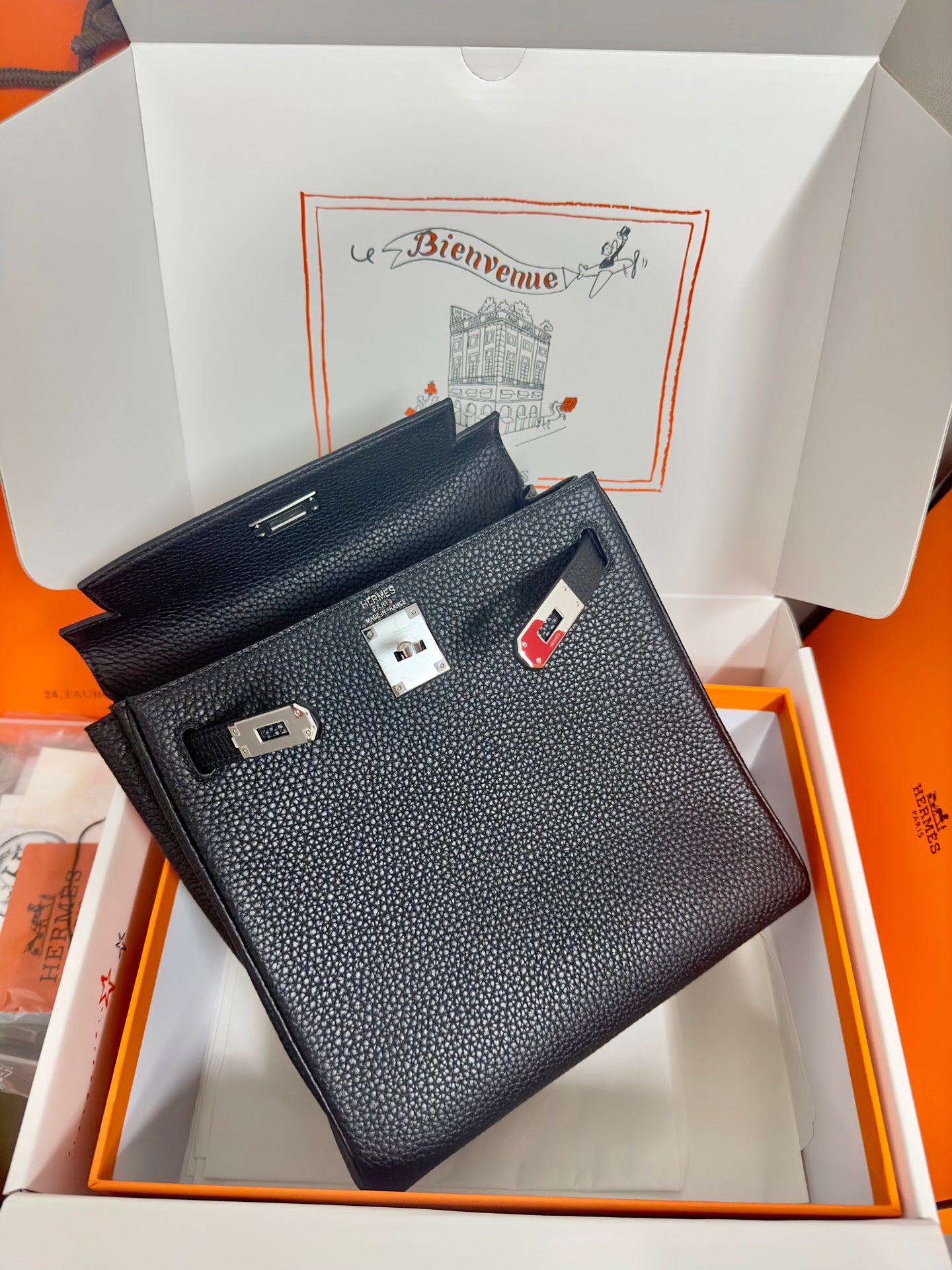 Hermes handbag top view in dark textured leather, showing belt strap and clasp hardware.