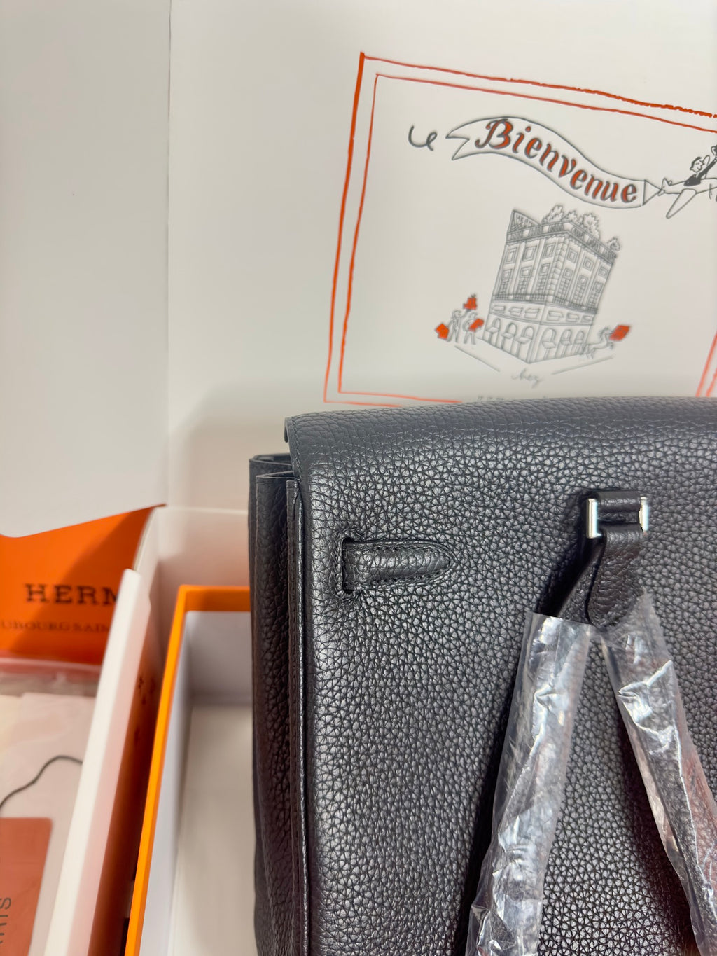 Hermes handbag front close-up in dark textured leather with flap details and hardware.