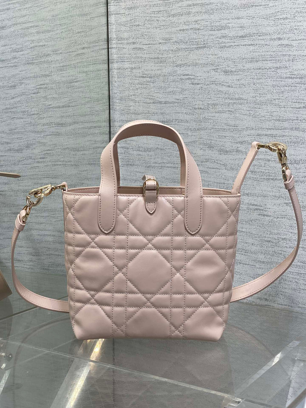 Quilted pale pink tote-style handbag with top handles and crossbody strap