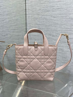 Quilted pale pink tote-style handbag with top handles and crossbody strap