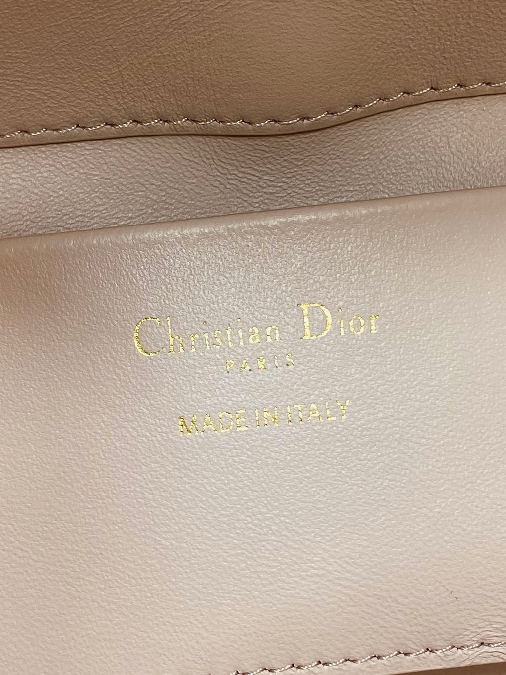 Leather stamp with Christian Dior Paris on pale pink handbag lining