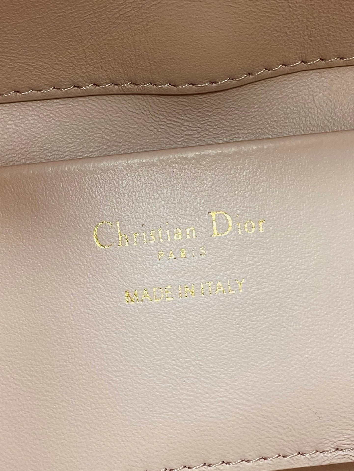 Leather stamp with Christian Dior Paris on pale pink handbag lining
