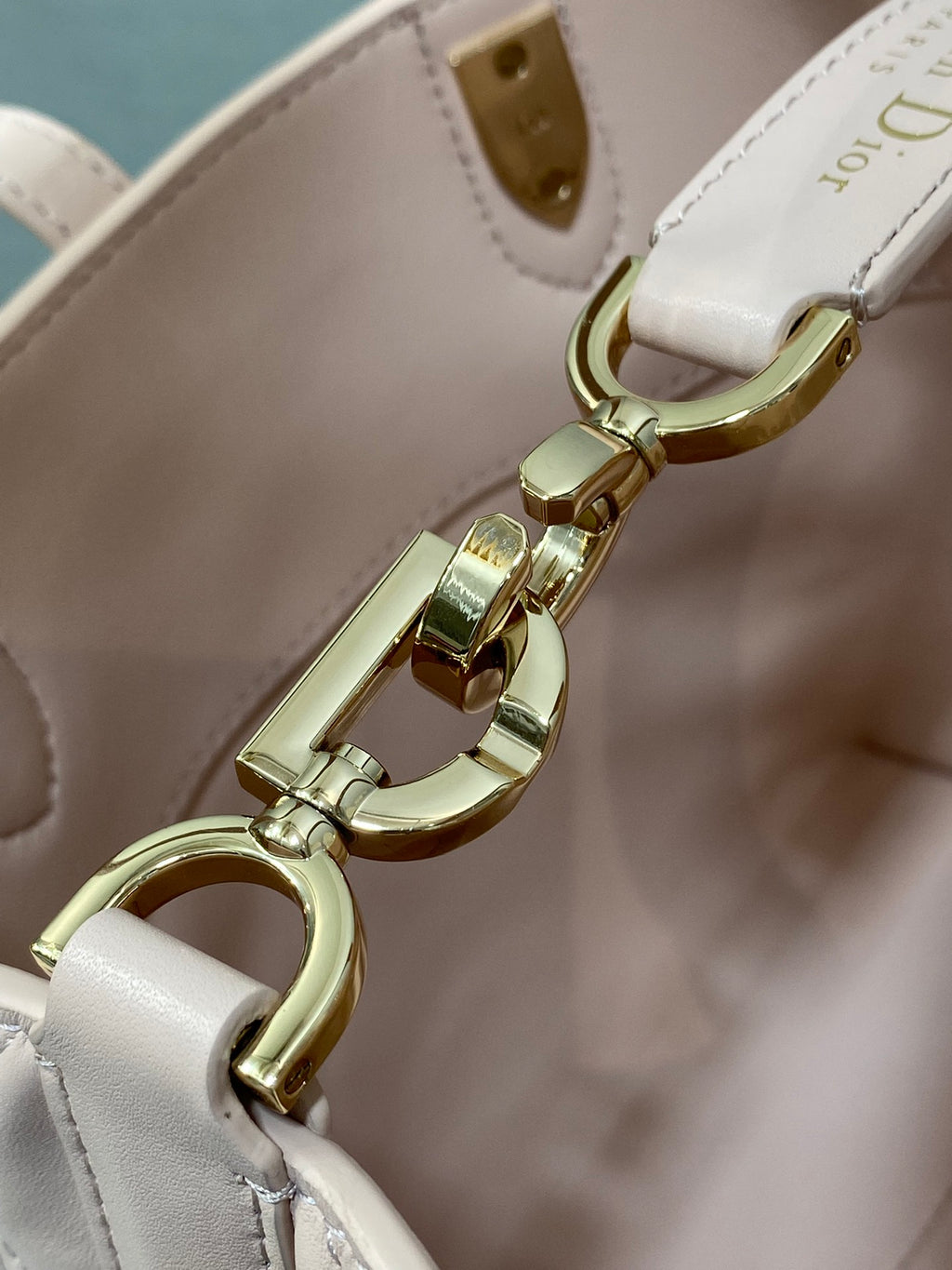 Gold clasp and ring hardware on pale pink handbag crossbody strap