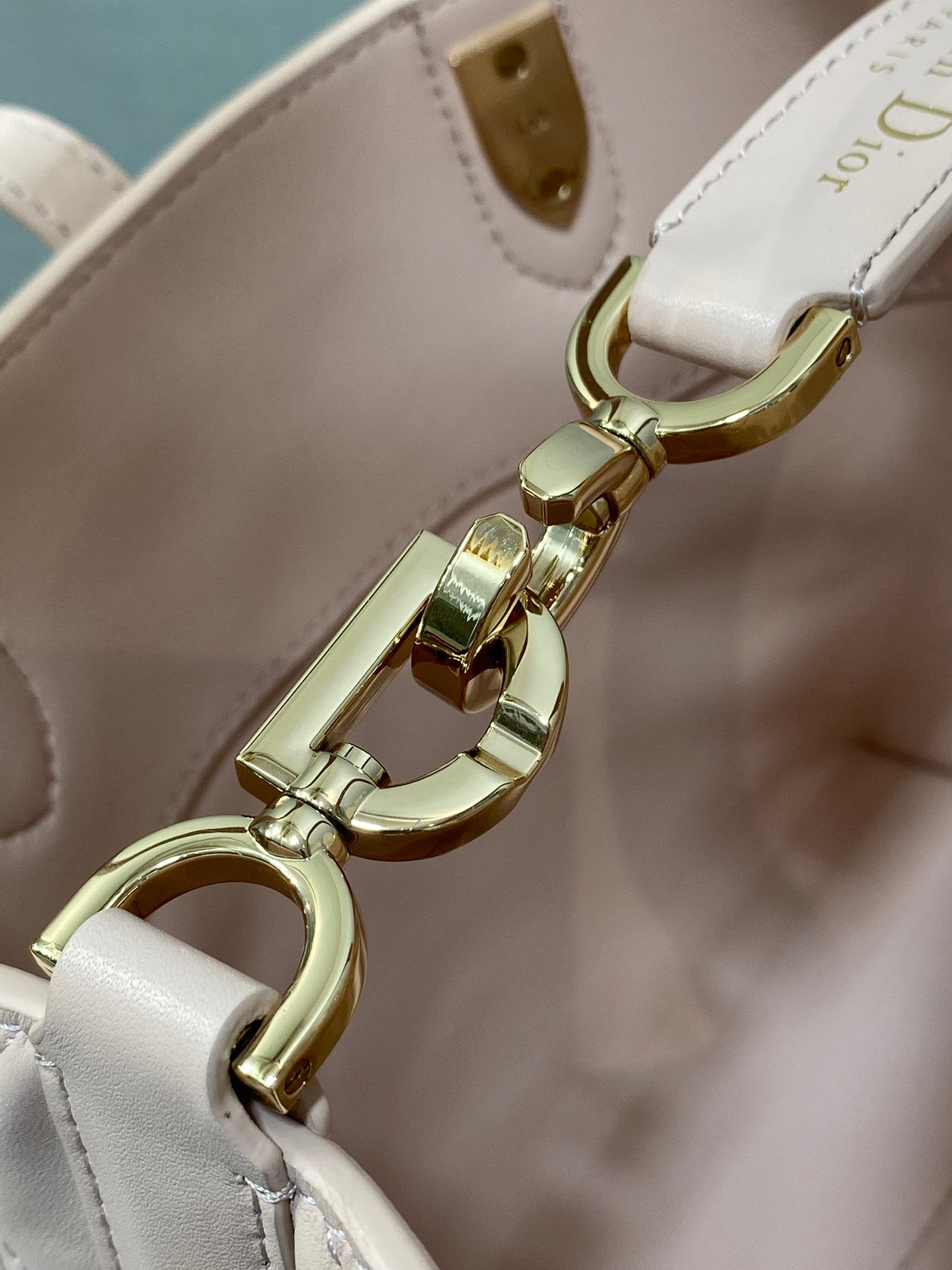 Gold clasp and ring hardware on pale pink handbag crossbody strap