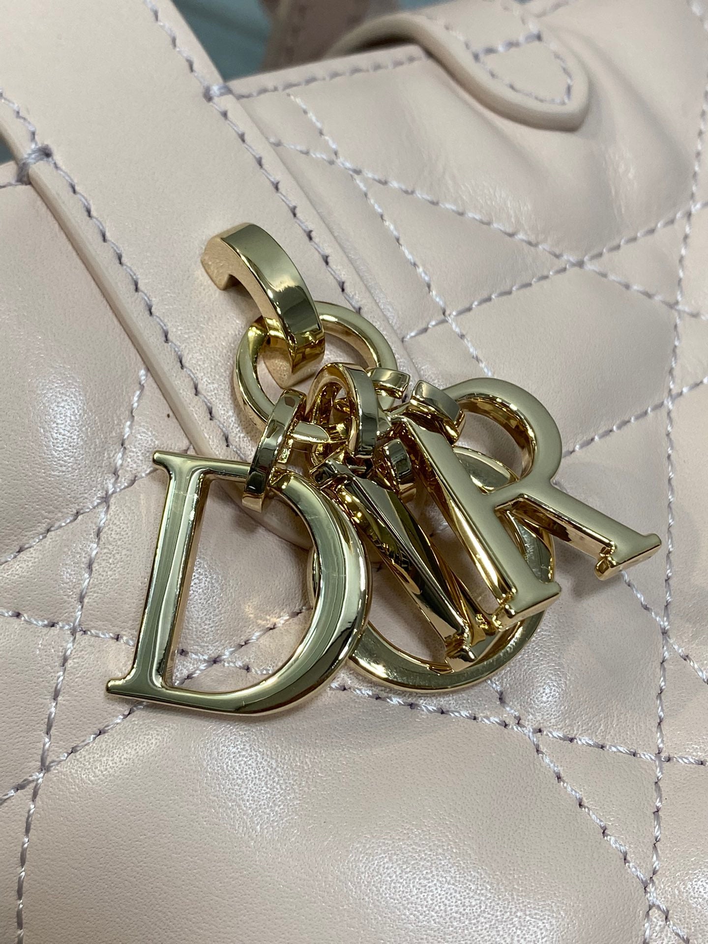 Dior logo charm with gold-tone hardware on quilted light pink bag
