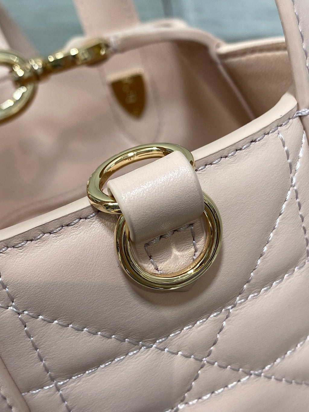 Dior mini bag strap attachment with gold-tone rings and light pink quilted stitching