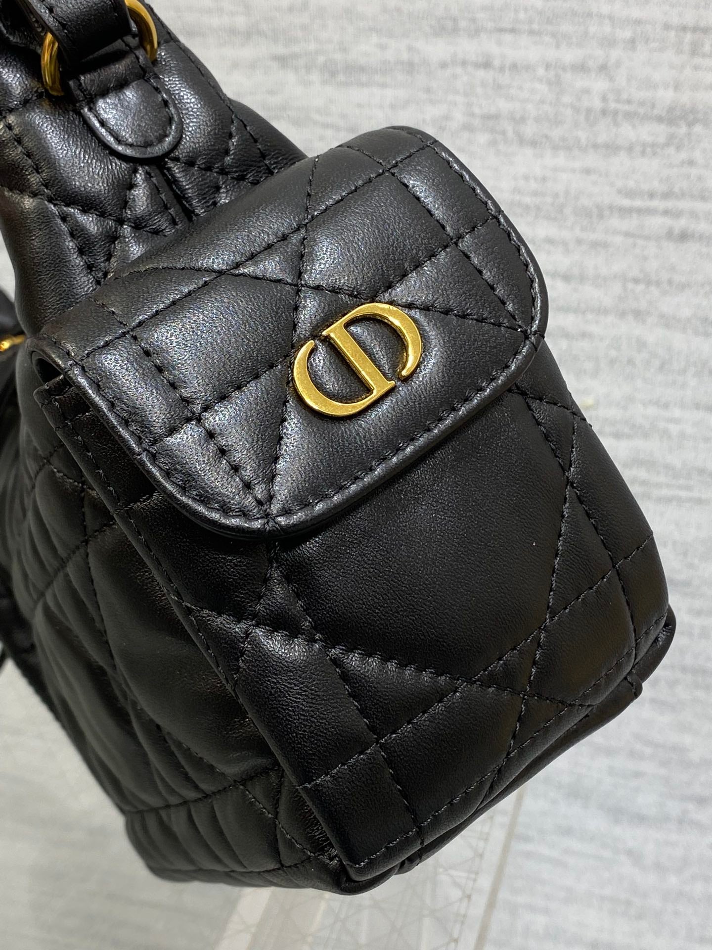 Quilted black leather flap bag with gold Dior-style logo at the front