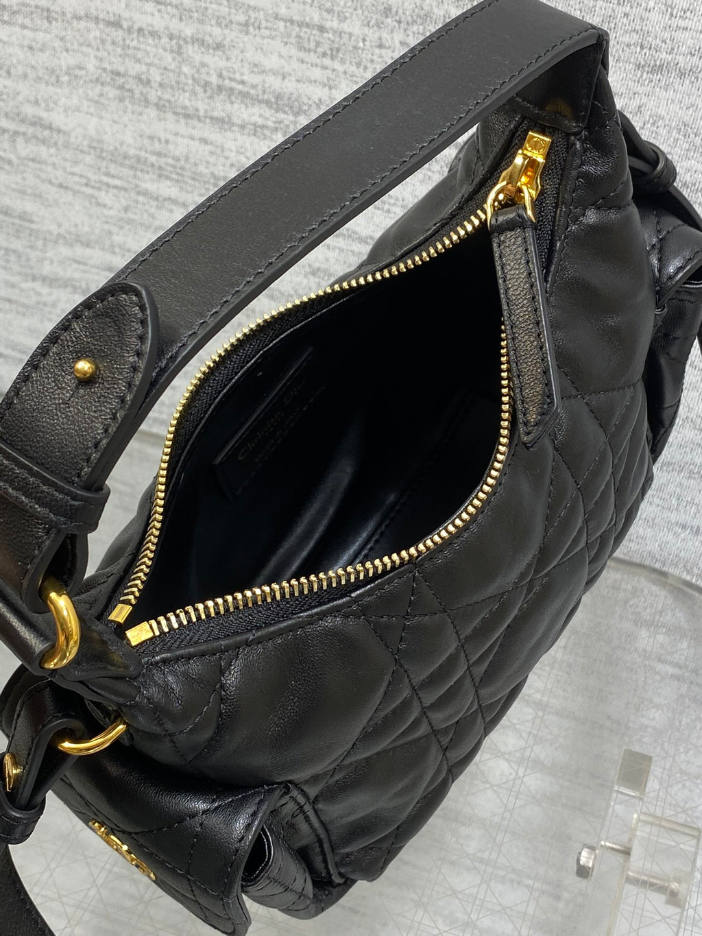 Black quilted bag with open top and gold-tone zipper, lined interior