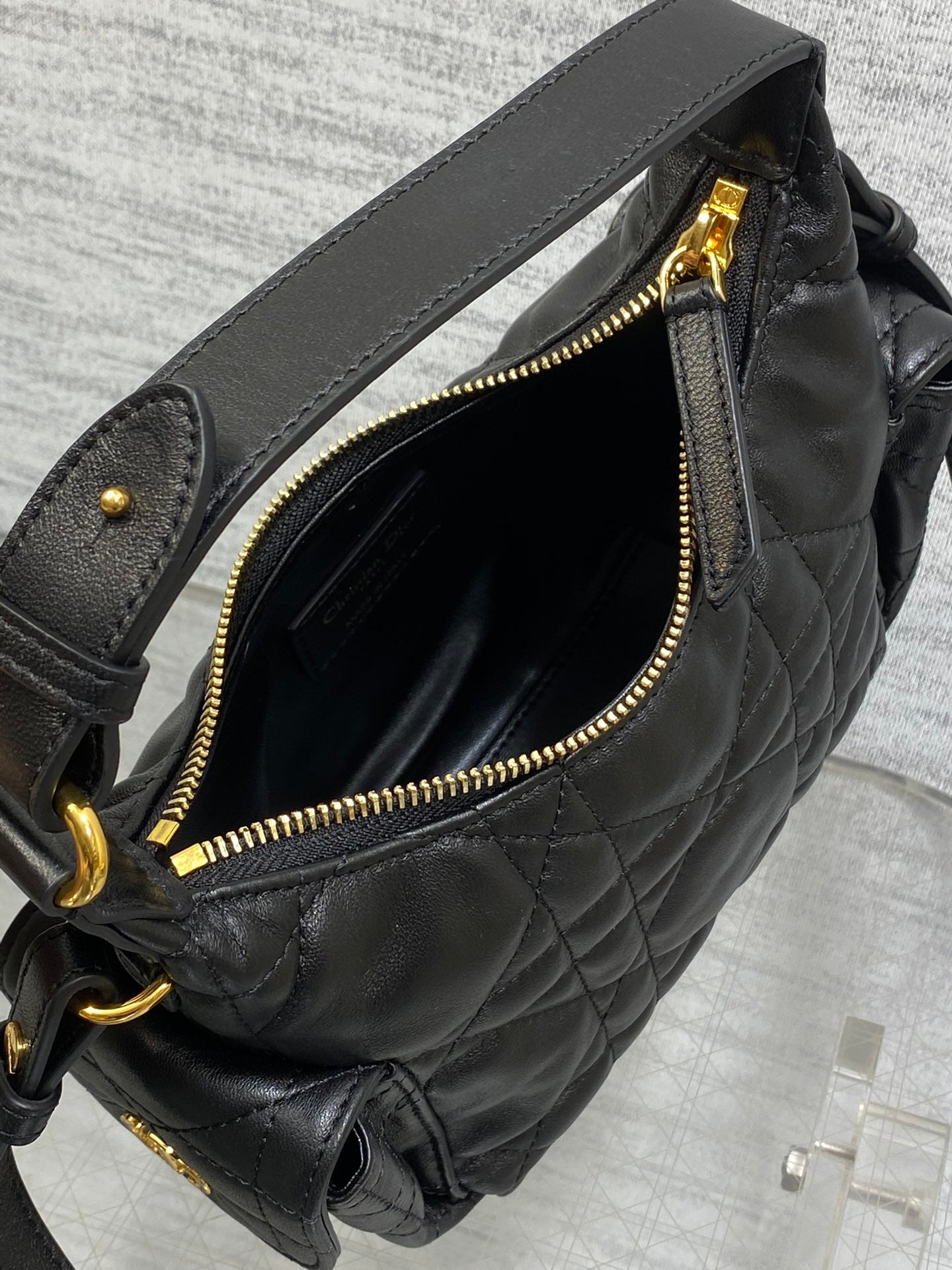 Black quilted bag with open top and gold-tone zipper, lined interior