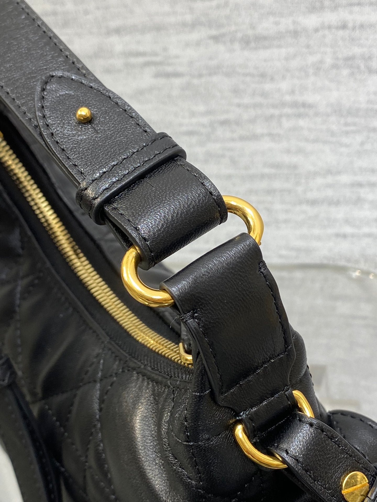 Quilted black leather bag with gold-tone rings and side zipper pull detail