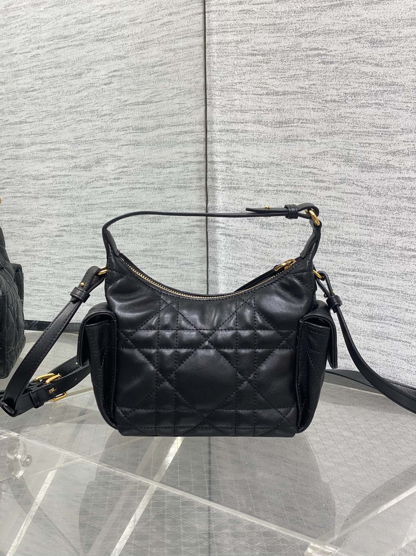 Quilted black leather shoulder bag with gold-tone hardware, side pockets, and strap