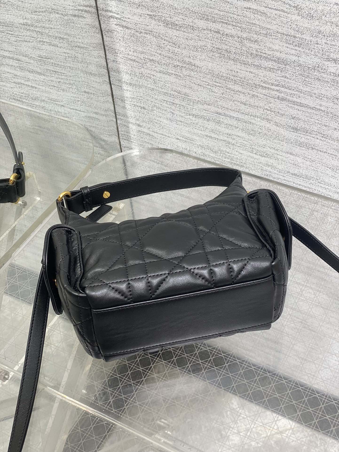 Black quilted shoulder bag with top flap and long crossbody strap, gold accents