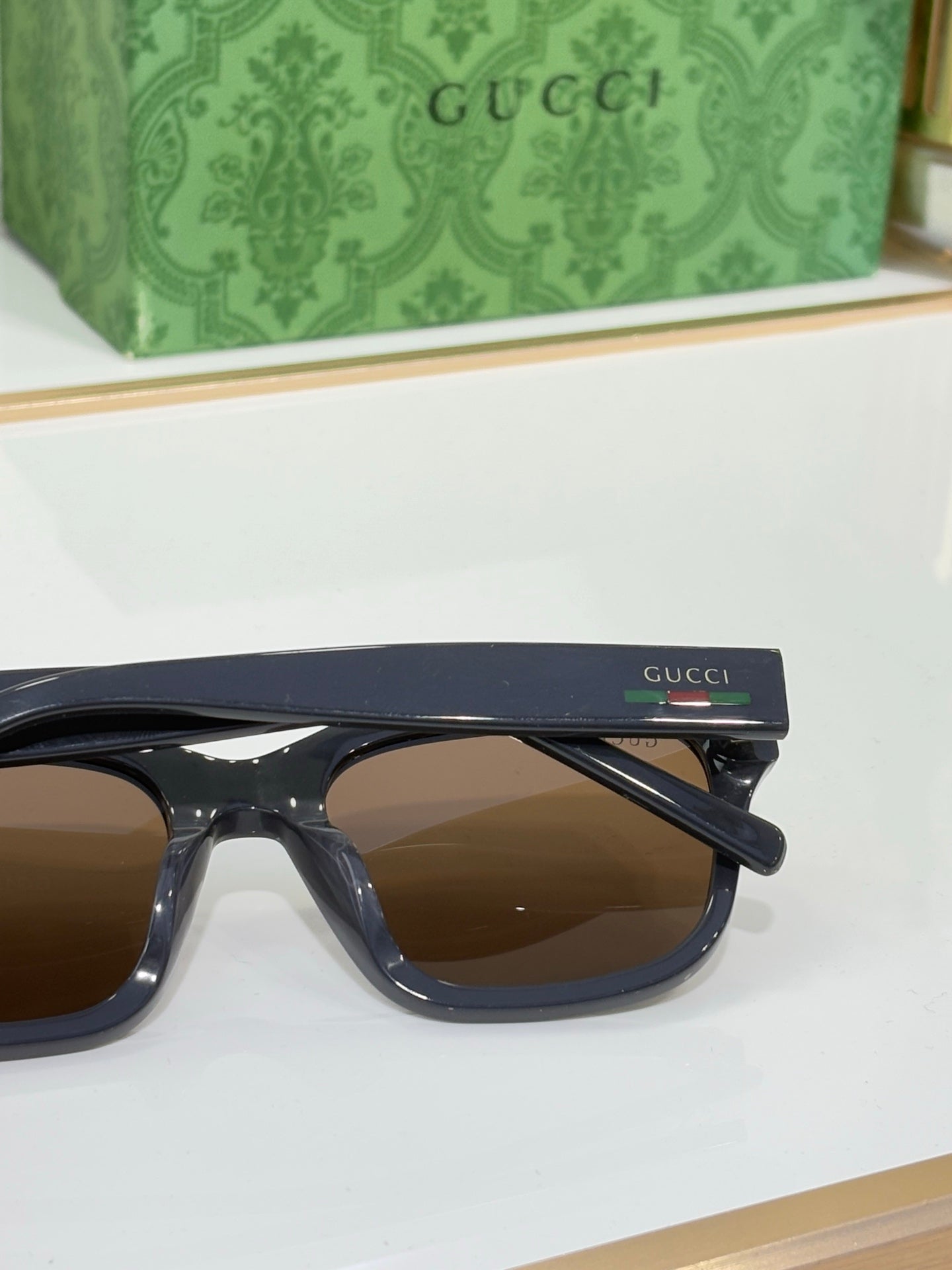 Gucci sunglasses side view with dark blue frames and brown-tinted lenses