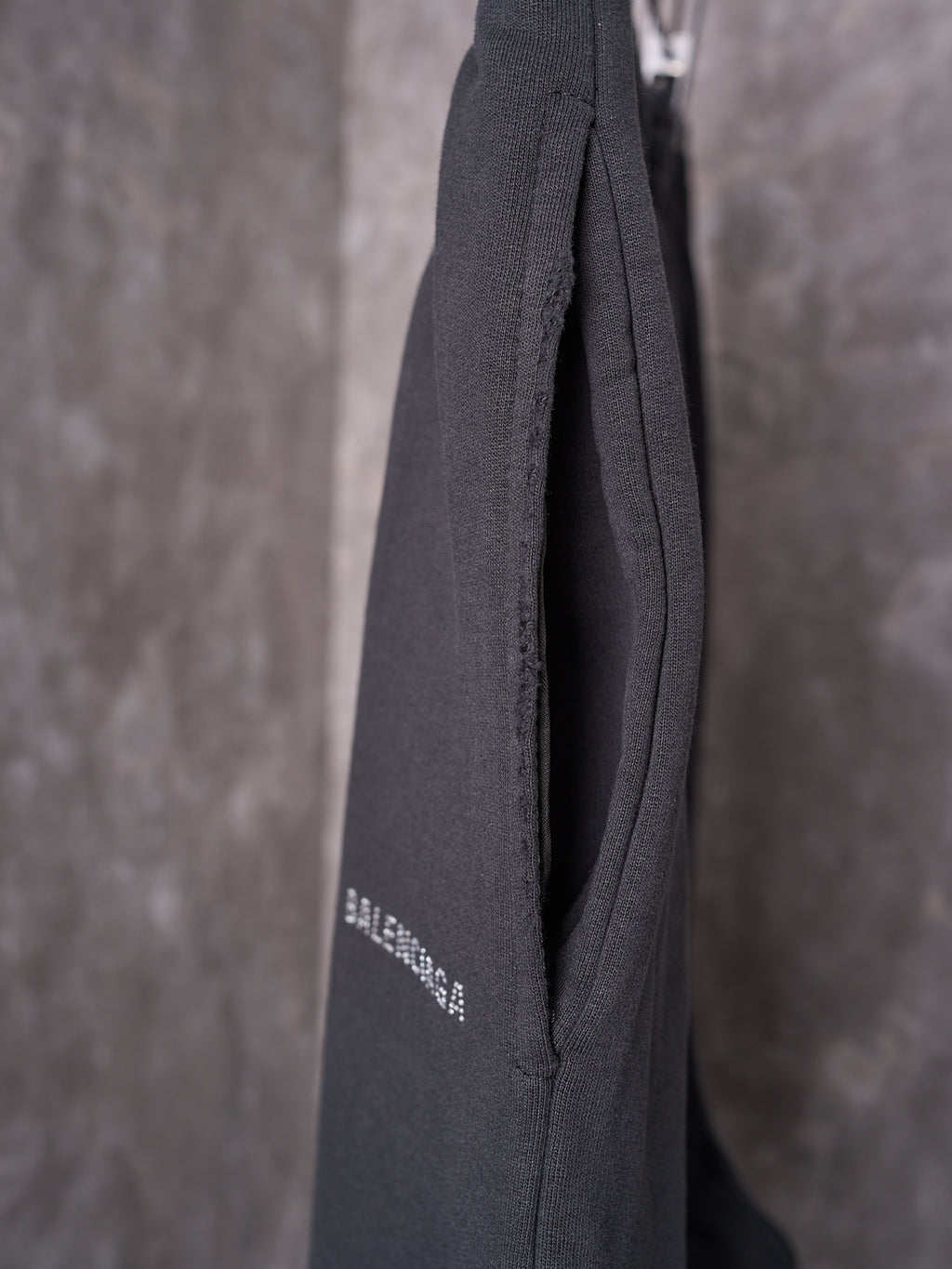 Black shorts back hem closeup with subtle logo print and textured seam.