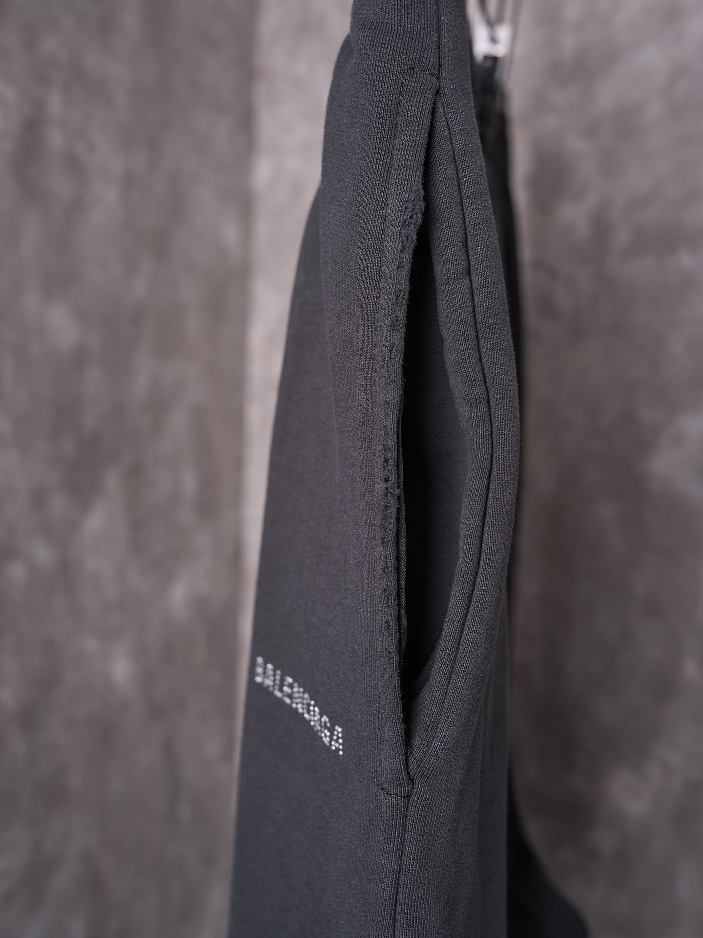 Black shorts back hem closeup with subtle logo print and textured seam.