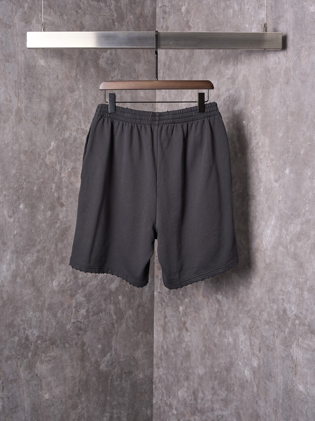 Black shorts with elastic waistband, relaxed leg, and scalloped hem edge.