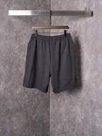 Black shorts with elastic waistband, relaxed leg, and scalloped hem edge.