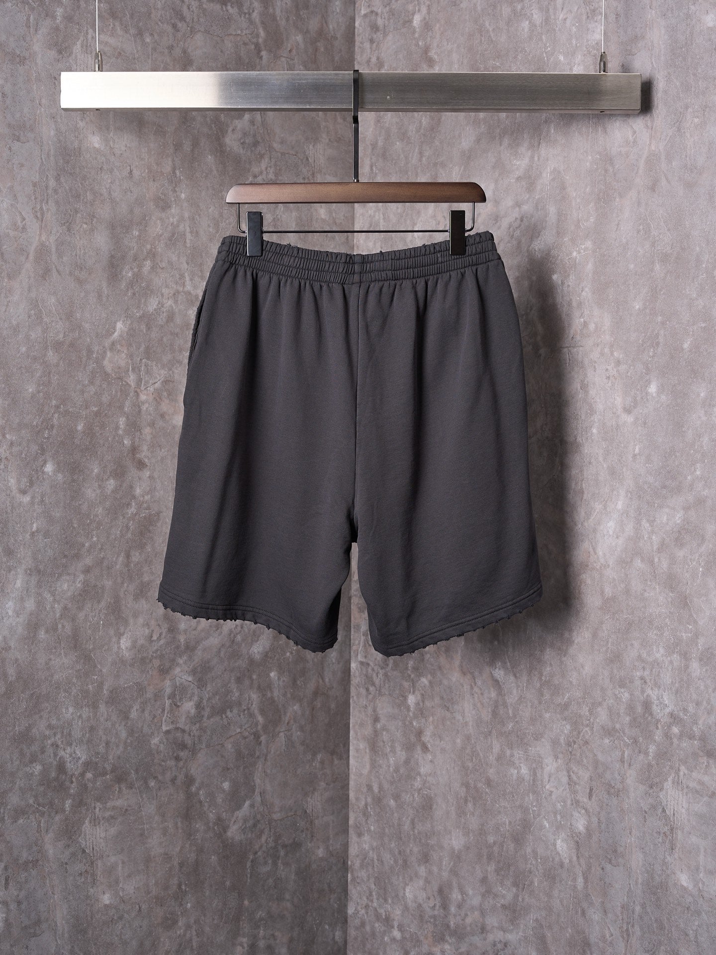 Black shorts with elastic waistband, relaxed leg, and scalloped hem edge.