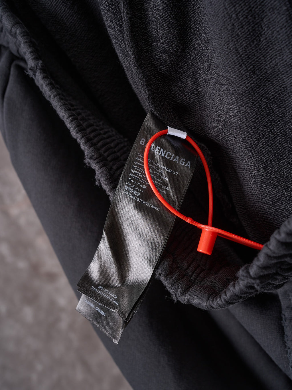 Black shorts closeup with inner tag and red security tether near hem.